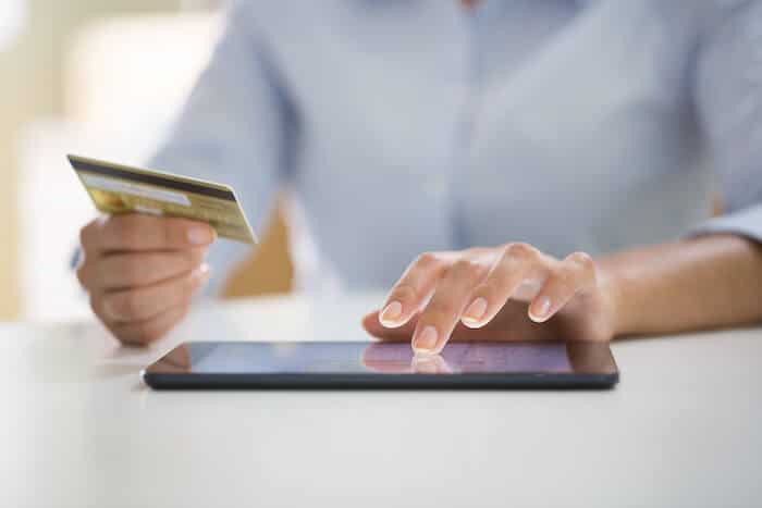 Person using a tablet and holding a credit card